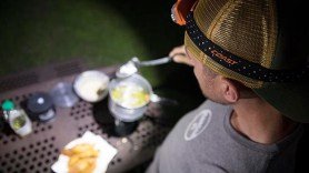 Nick frying fish in tempura batter on picnic table with COAST headlamp during Field Trip: Great River Road.