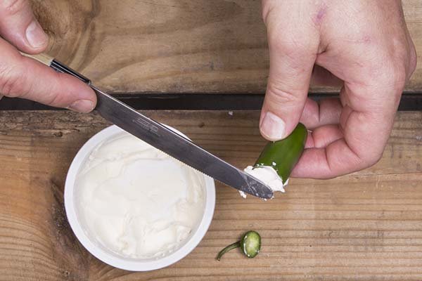 stuffing cream cheese into the jalapeno.