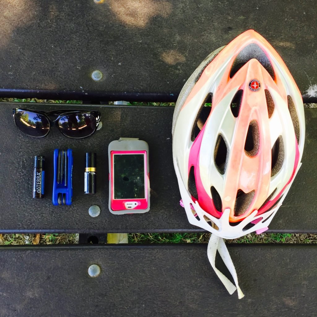 Diana's Gear - Clockwise: Sunglasses, helmet, phone, lipstick, doTERRA Peppermint Beadlets, ”>bike tool,, doTERRA Peppermint Beadlets.