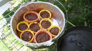 Campfire birthday cake cupcakes in citrus halves lined up in a lined Dutch oven.