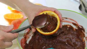 Spooning batter into citrus halves for campfire birthday cake cupcakes in citrus halves.