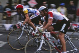 Greg LeMond (red helmet) stands to pedal during the Fisherman's Wharf Criterium stage of the 1986 Coors Classic in San Francisco. A Team 7-Eleven rider corners on LeMond's left.