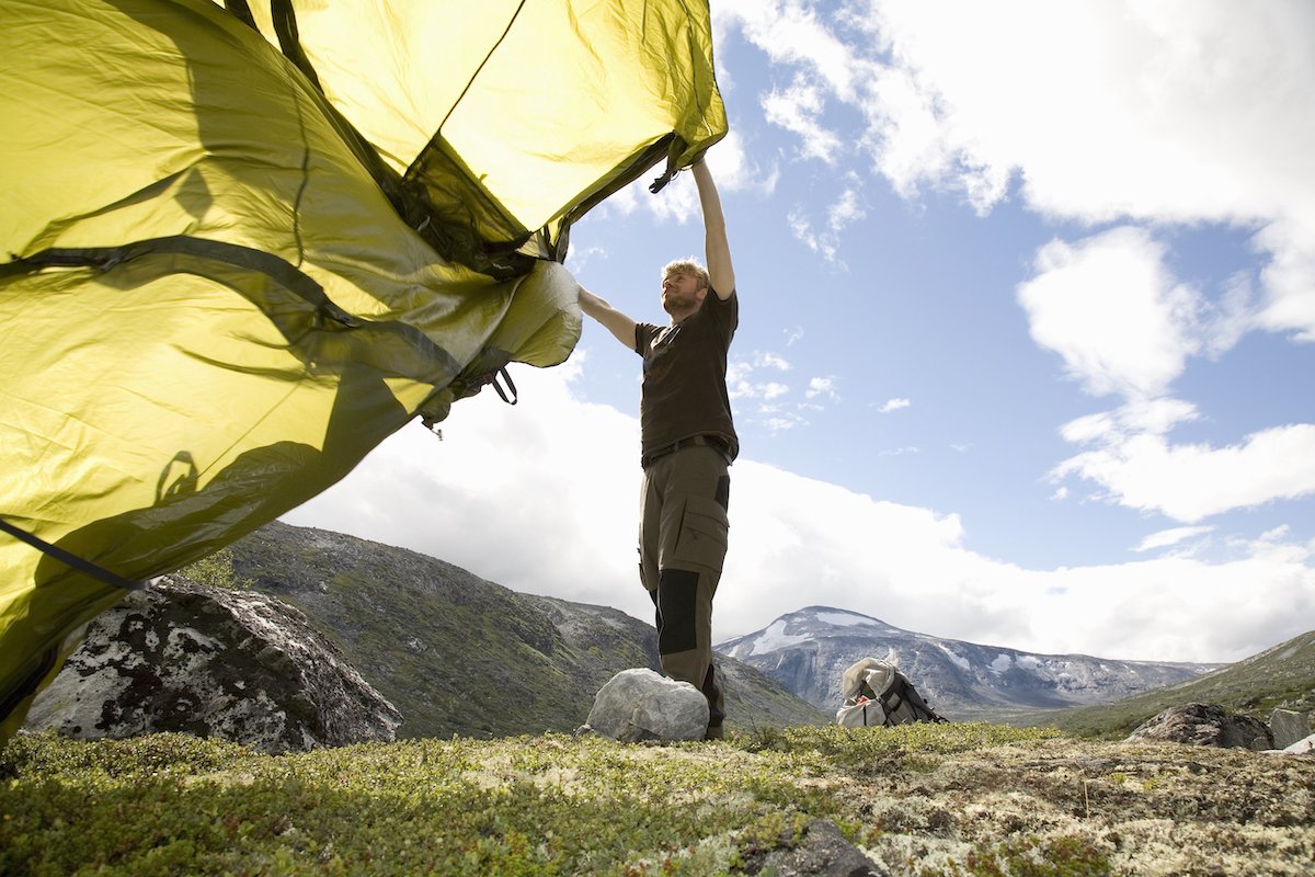 Man wildcamping, setting up tent