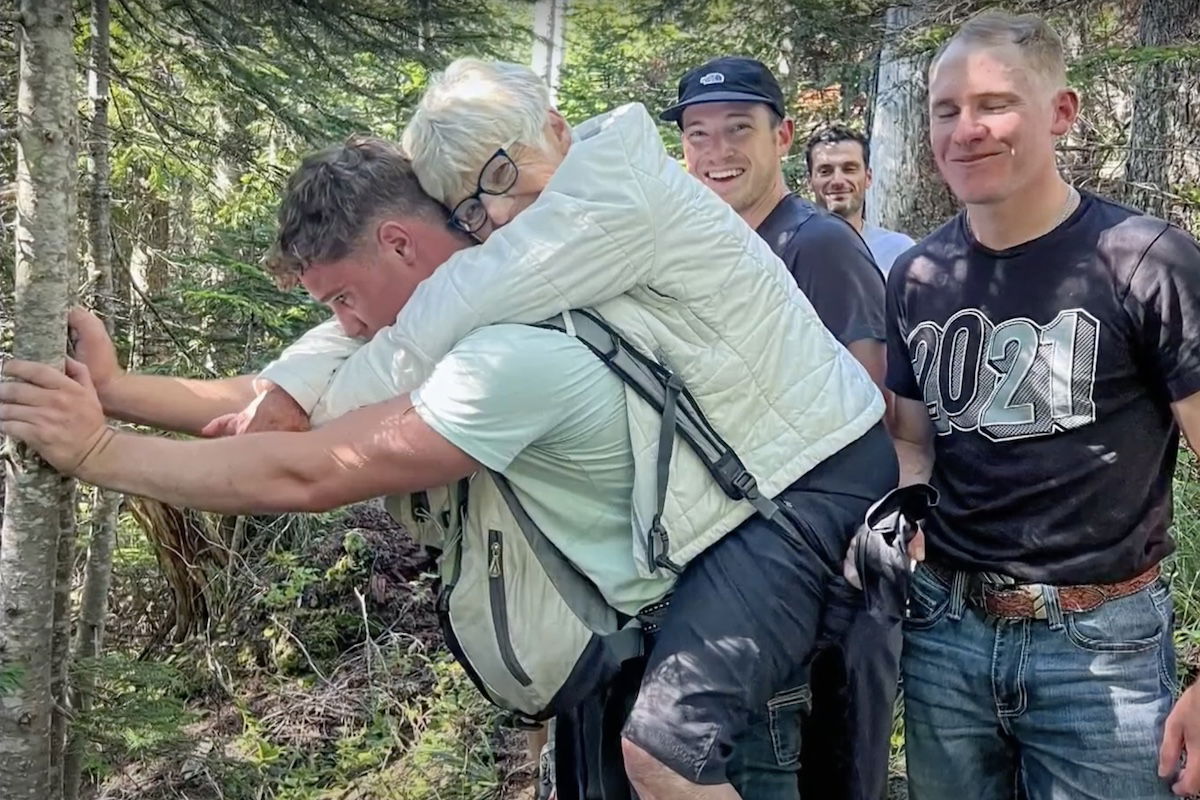 man carries hiker down mountain