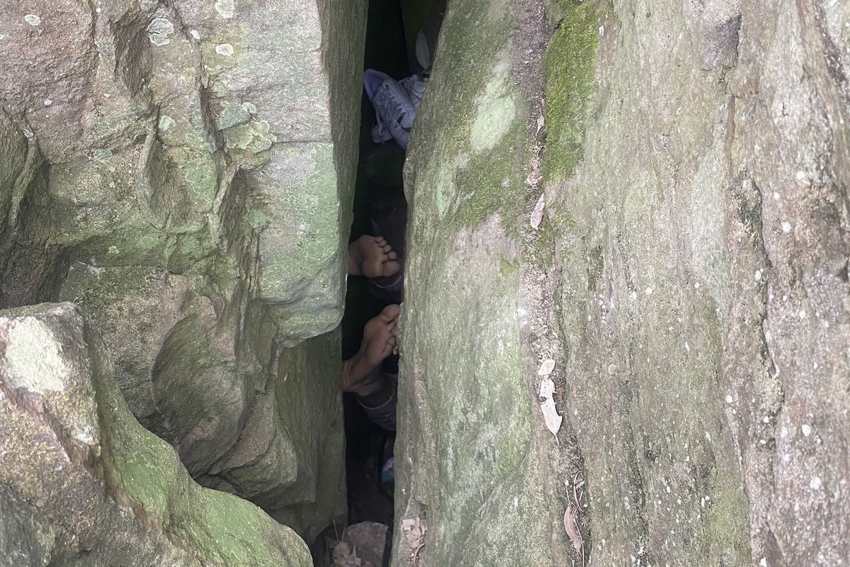 woman stuck between boulders trying to retrieve phone